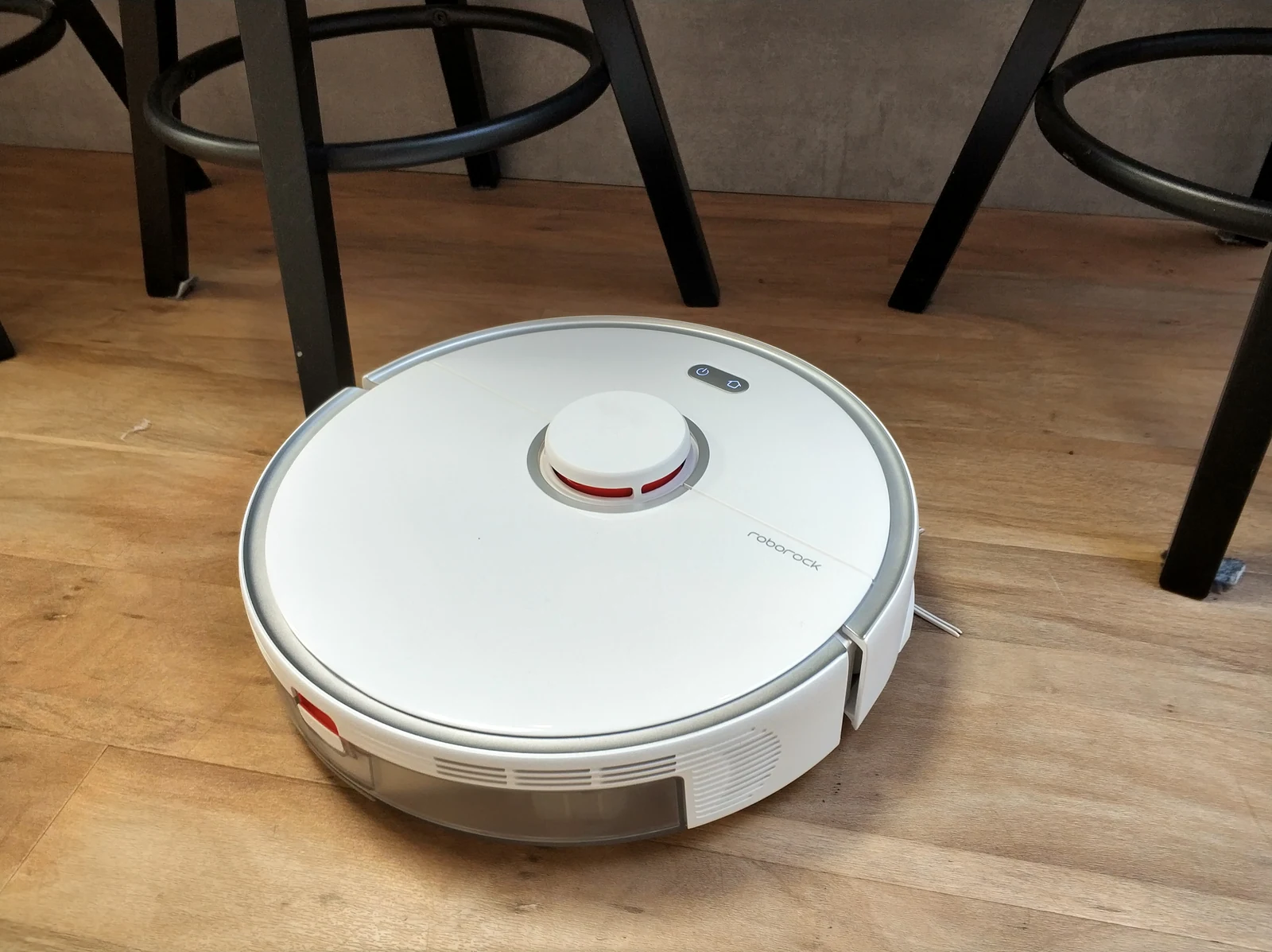 Робот-пылесос Roborock S5 Max на деревянном полу между ножками стульев